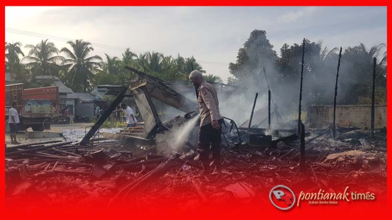 Petugas Polsek Jawai Selatan memadamkan sisa api yang membakar puing-puing bangunan rumah milik Abun yang terbakar, Rabu (15/2/2023)