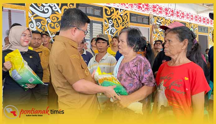 Satono menyerahkan beras ukuran 5 kg kepada warga dalam Gerakan Pangan Murah (GPM) di di Rumah Betang Ria Tanik Dusun Sungai Enau